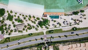 An aerial view of a resort with a swimming pool, beach, palm trees, and a road. - 2-level Retreat Jacuzzi Free Airport Transfer (Punta Cana)