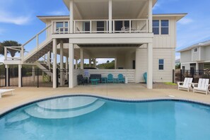 Ein zweistöckiges Haus mit Swimmingpool, Gartenmöbeln und einer überdachten Terrasse.