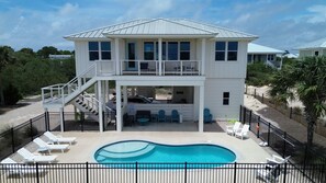 Ein zweistöckiges Haus mit Pool, Außenbereich zum Sitzen und einem umzäunten Patio.