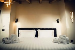 Une chambre d’hôtel avec un grand lit, deux lampes de chevet et des serviettes portant la marque « TRIPART ».