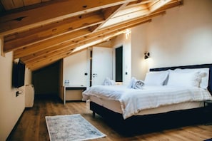 A bedroom with a wooden ceiling, a bed with white bedding, a bedside table, and a wall-mounted light fixture. - Hotel Triart Korce  (Korçë)