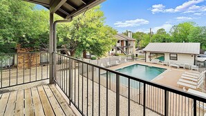Une terrasse en bois avec une piscine, des chaises longues et un espace abrité.