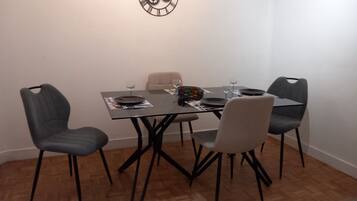 A dining area with a table set for four, including plates, glasses, and a bottle.
