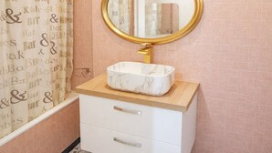 Een badkamer met een marmeren wastafel, een gouden kraan en een spiegel met een gouden lijst.