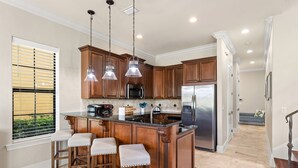 Una cocina con armarios de madera, un refrigerador de acero inoxidable y una barra con taburetes.
