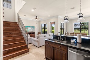 A kitchen with a wooden staircase, a dining area with a view, and a ceiling fan. - Golf Course Home with 4 King Beds and a Golf Cart (Miramar Beach)