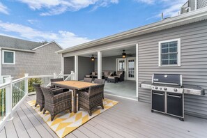 Eine überdachte Terrasse mit Grill, Korbmöbeln und Blick ins Haus.