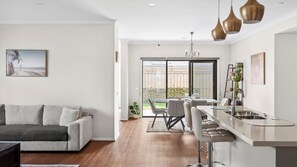Eine moderne Küche mit Bar, einem Esstisch mit Stühlen und einem Sofa im Wohnzimmer.
