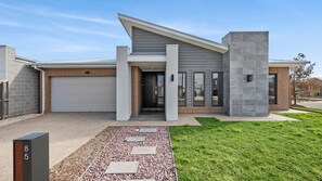 Ein modernes, zweistöckiges Haus mit Garage, Veranda und gepflegtem Rasen.