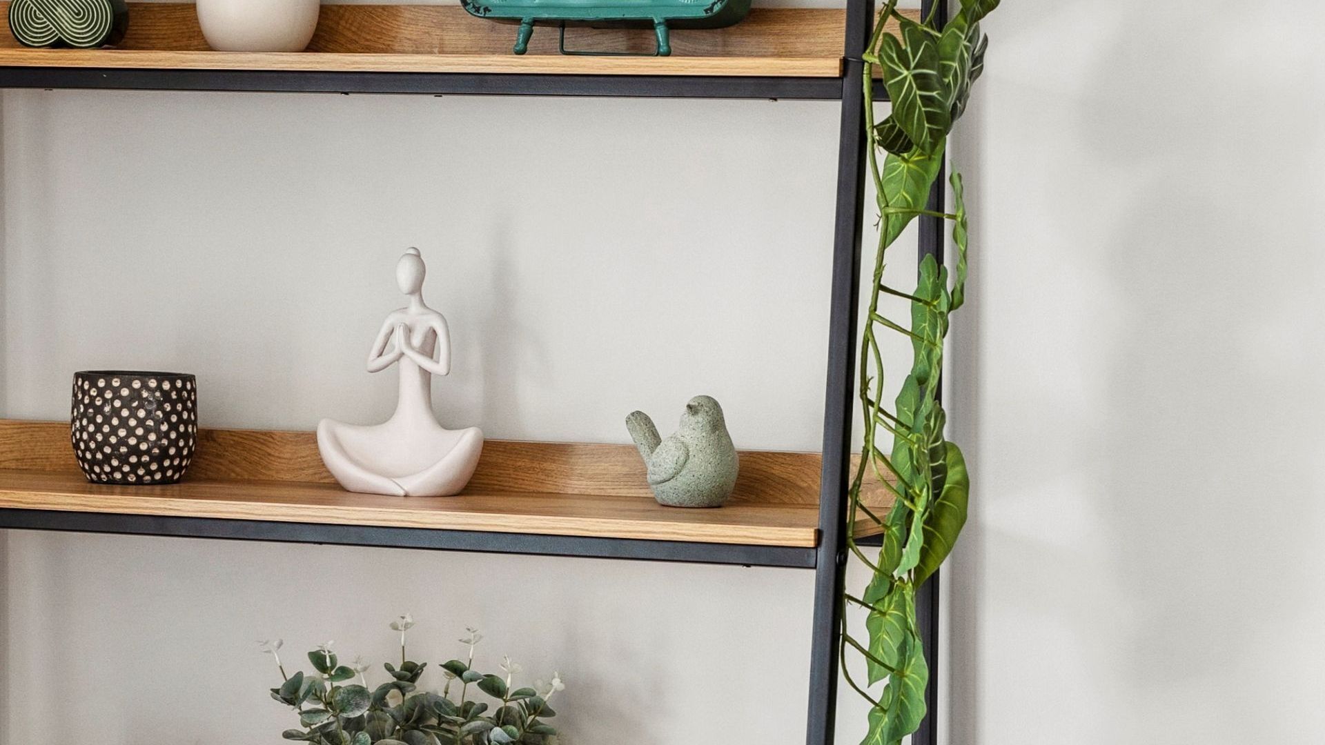 A shelf with a white statue, a polka-dotted cup, and a small figurine.