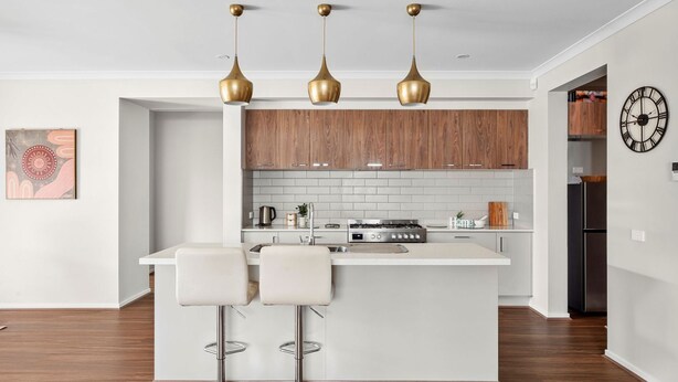 Una cocina moderna con una isla central, iluminación colgante y armarios de madera.
