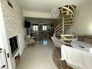 Ein modernes Wohnzimmer mit Kamin, Essbereich und Wendeltreppe.