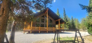 Eine Lodge mit einer Holzterrasse, großen Fenstern und einer überdachten Veranda.