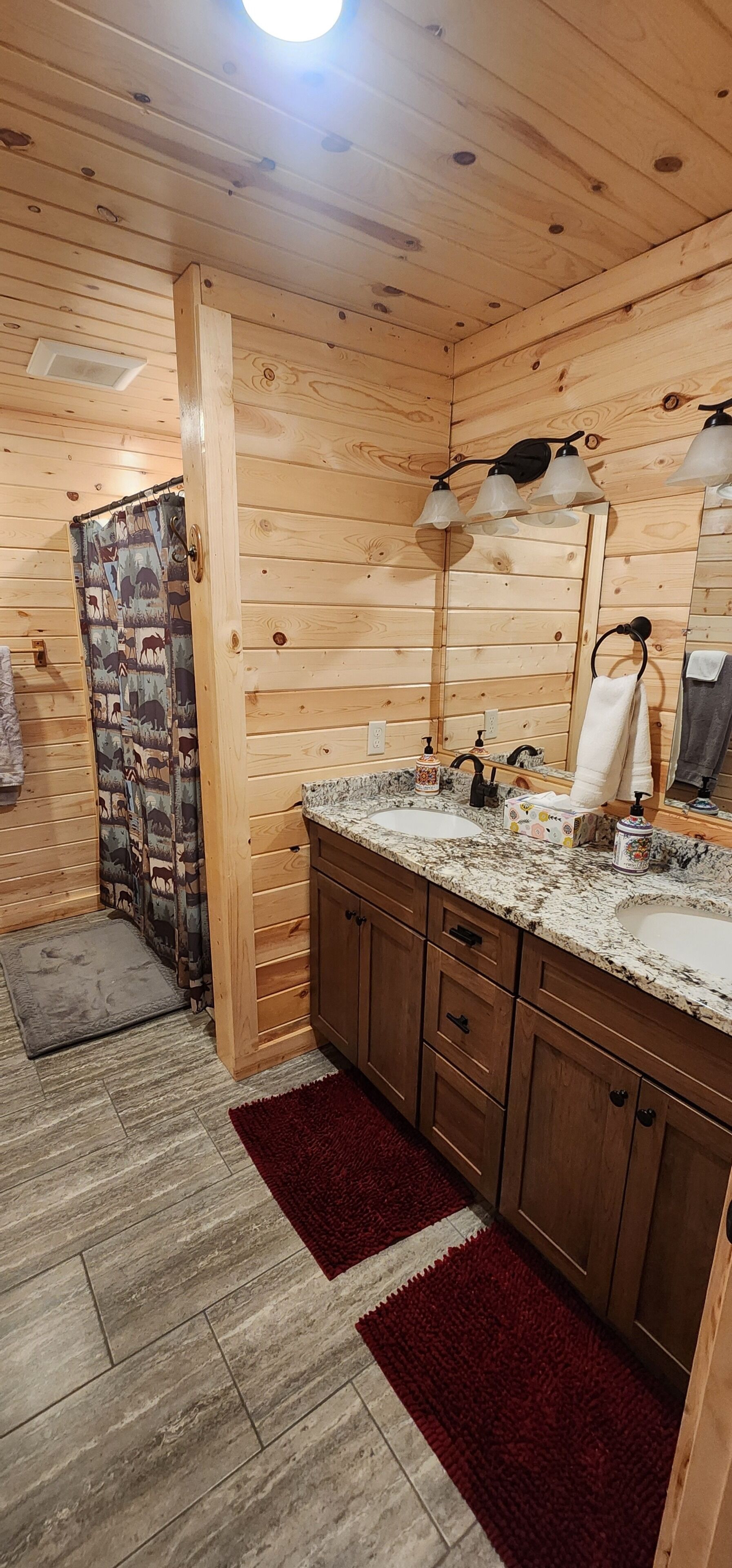 Ein Badezimmer einer Holzhütte mit Waschbecken, Spiegel und Handtuchhalter.