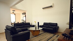 A modern living room with a round coffee table, two black sofas, a wooden coffee table base, a rug, and a small statue on a side table. - ROOM WITH PRIVATE BATHROOM, IN A HOUSE WITH SHARED AMENITIES AND A POOL (Palmira)