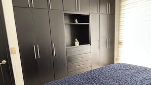 A bedroom with a large bed, dark wardrobe, and a small shelf with a plant. - ROOM WITH PRIVATE BATHROOM, IN A HOUSE WITH SHARED AMENITIES AND A POOL (Palmira)