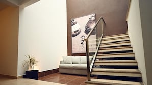 A staircase with a handrail, a potted plant, a sofa, and a poster on the wall. - ROOM WITH PRIVATE BATHROOM, IN A HOUSE WITH SHARED AMENITIES AND A POOL (Palmira)