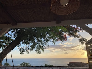 A view from a covered outdoor area with a wooden ceiling, overlooking a body of water and a distant horizon. - Ayana Lodge - Sea view &clim Bouillante (Bouillante)