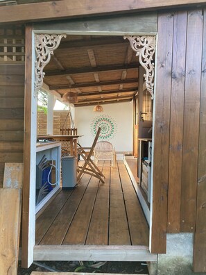 A wooden structure with a rustic interior, including a wooden bench, a wall with a circular design, and a hanging light fixture. - Ayana Lodge - Sea view &clim Bouillante (Bouillante)