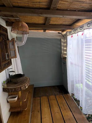 Eine Holzterrasse mit einem rustikalen Waschbecken, einem hängenden Korb und einer Bank.