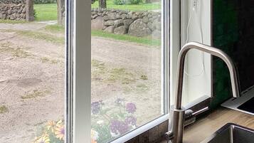 Una cocina con un grifo de acero inoxidable y vistas a un jardín a través de un ventanal grande.