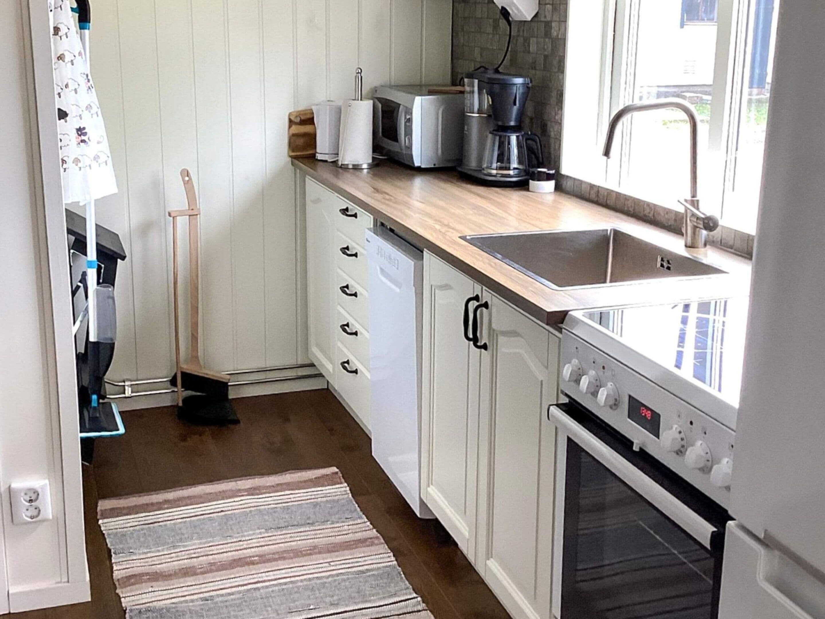 Een keuken met witte kasten, een houten aanrecht, een koffiezetapparaat, een broodrooster en een vaatwasser.