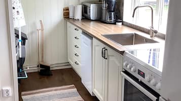 Een keuken met witte kasten, een houten aanrecht, een koffiezetapparaat, een broodrooster en een vaatwasser.