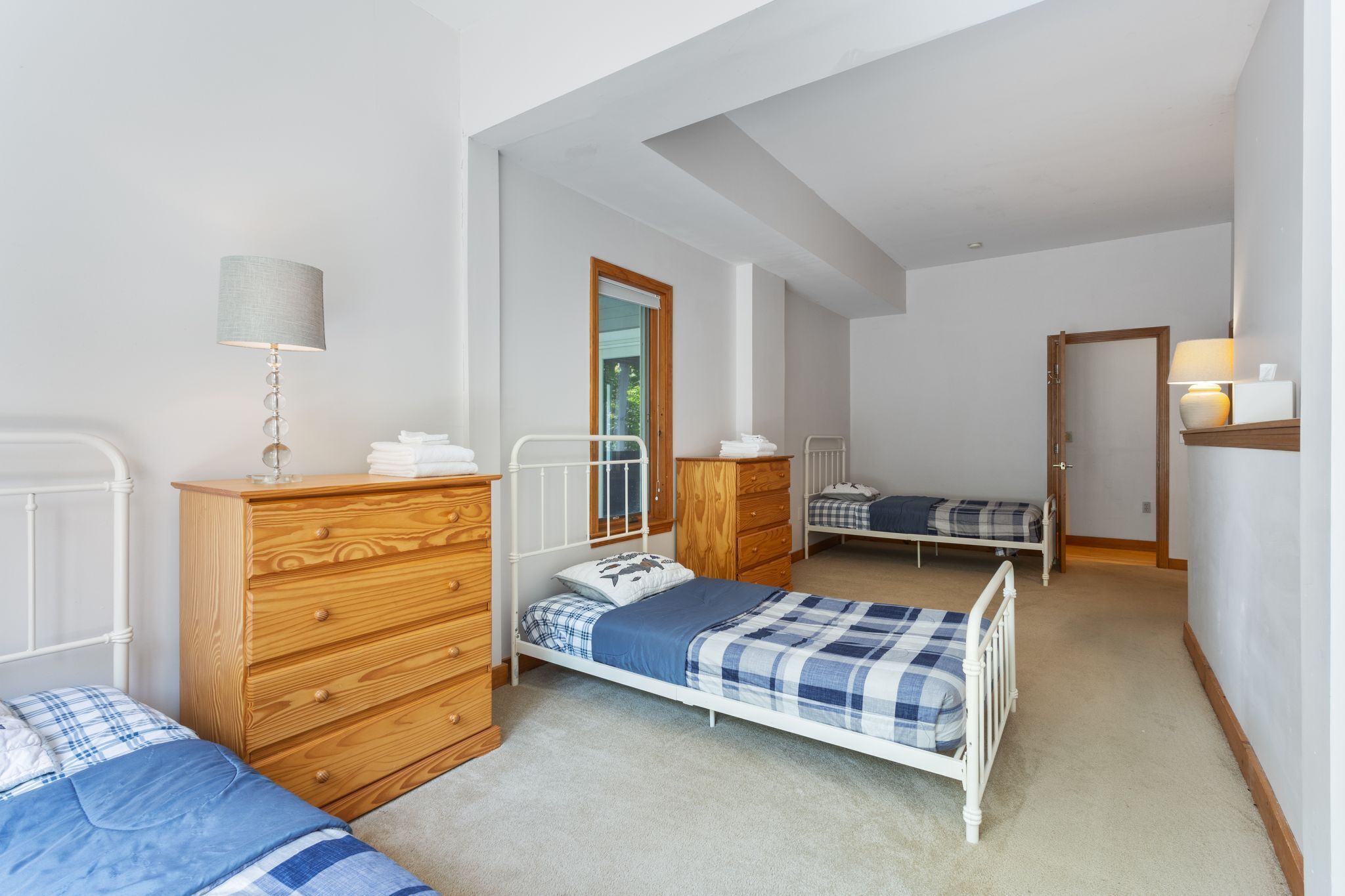 A bedroom with two beds, wooden furniture, a mirror, and a lamp.