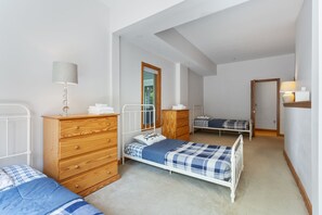 Un dormitorio con dos camas, muebles de madera, un espejo y una lámpara.