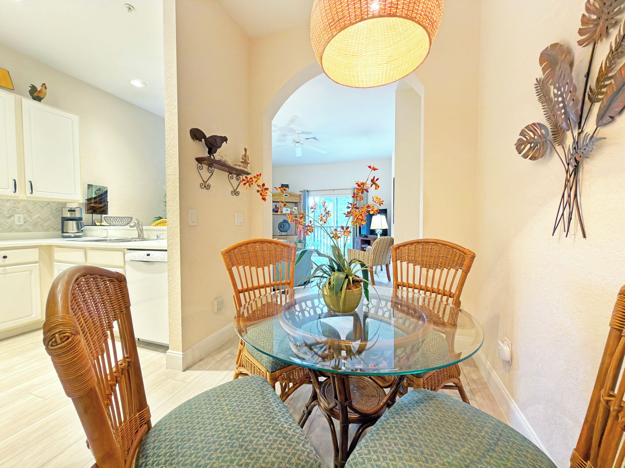 Un coin repas avec une table en verre, des chaises en osier et une plante décorative.
