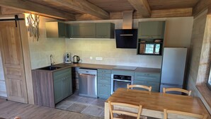 Eine Küche mit Holzausstattung, einem Geschirrspüler, einem Backofen und einem Kühlschrank.