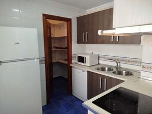 A kitchen with a white refrigerator, a microwave, a sink, and wooden cabinets.