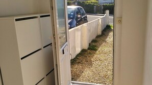 En døråbning der fører til en grusvej med en parkeret bil.