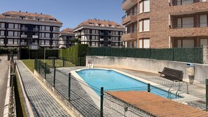 Ein von einem Zaun umgebener Swimmingpool, in der Nähe eine Bank und ein Mülleimer.