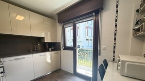 Eine moderne Küche mit weißen Schränken, einer Mikrowelle und einem Essbereich mit Tisch und Stühlen.