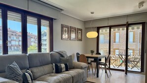 Ein modernes Wohnzimmer mit Sofa, Esstisch und Blick durch große Fenster.