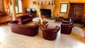Ein geräumiges Wohnzimmer mit Kamin, Ledersofas und Fernseher.