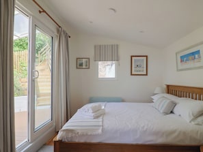 Quarto com cama, janela e porta que dá para uma varanda.
