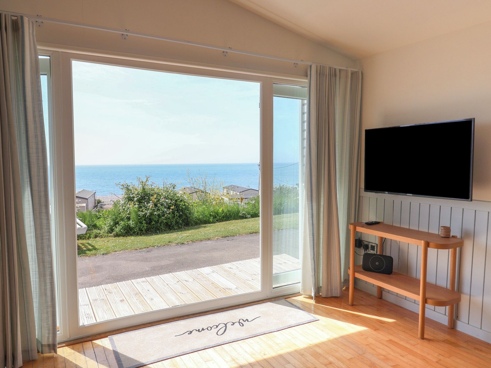 Una habitación con un amplio ventanal corredera que da a una terraza con vista al mar.