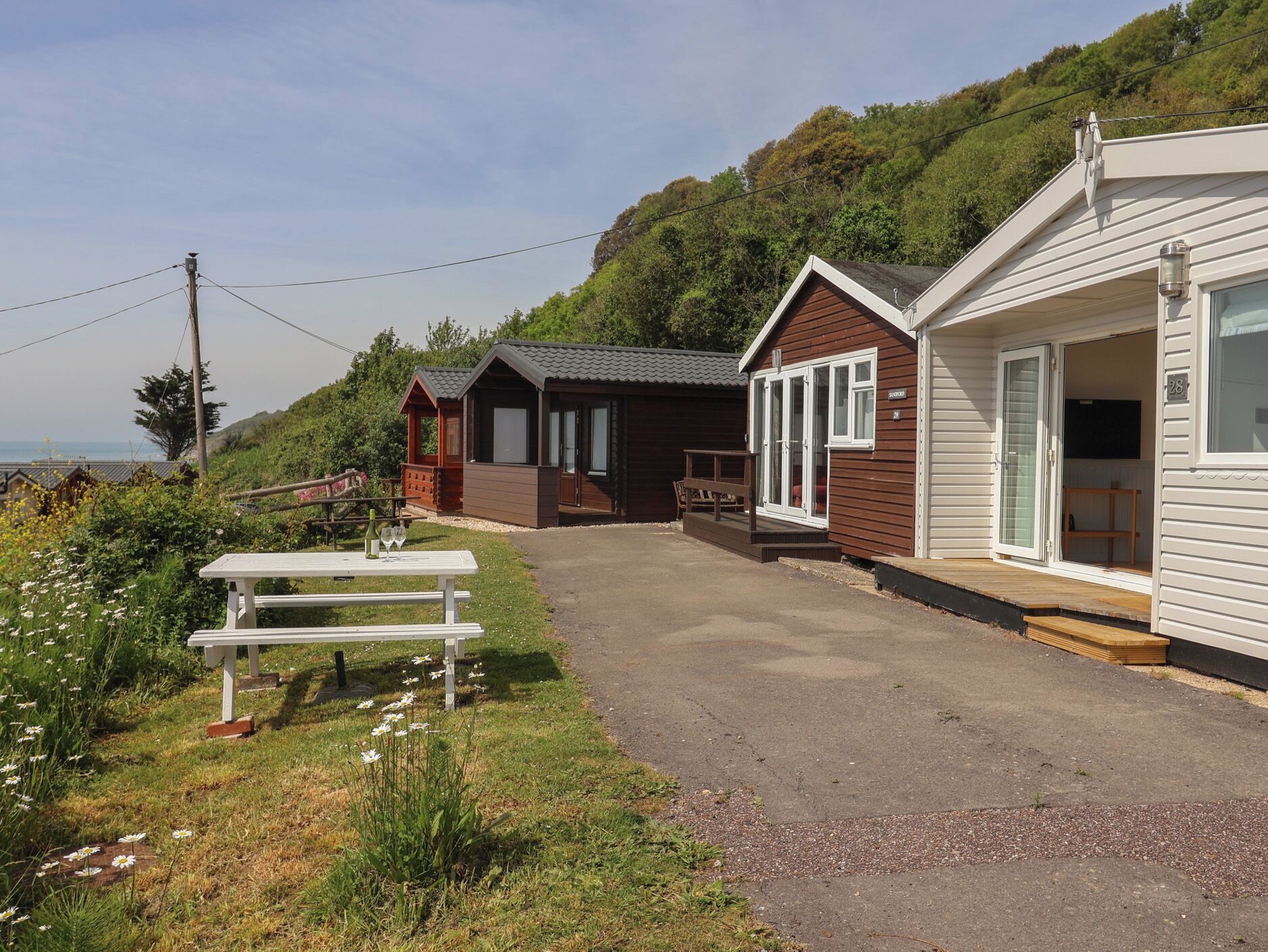 A row of cabins with a picnic table and a view of the sea.