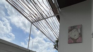 Un espacio de estar al aire libre cubierto con suelo estampado, una pared con plantas y un cuadro.