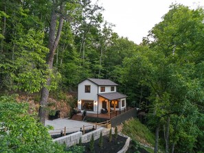 Ein zweistöckiges Haus mit einer Terrasse, umgeben von dichtem Wald.