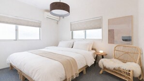 A bedroom with a bed, bedside tables, a chair, and a hanging light fixture. - Spacious 1,500 sq ft Japanese Bath House with 7 Bedrooms (Osaka City)