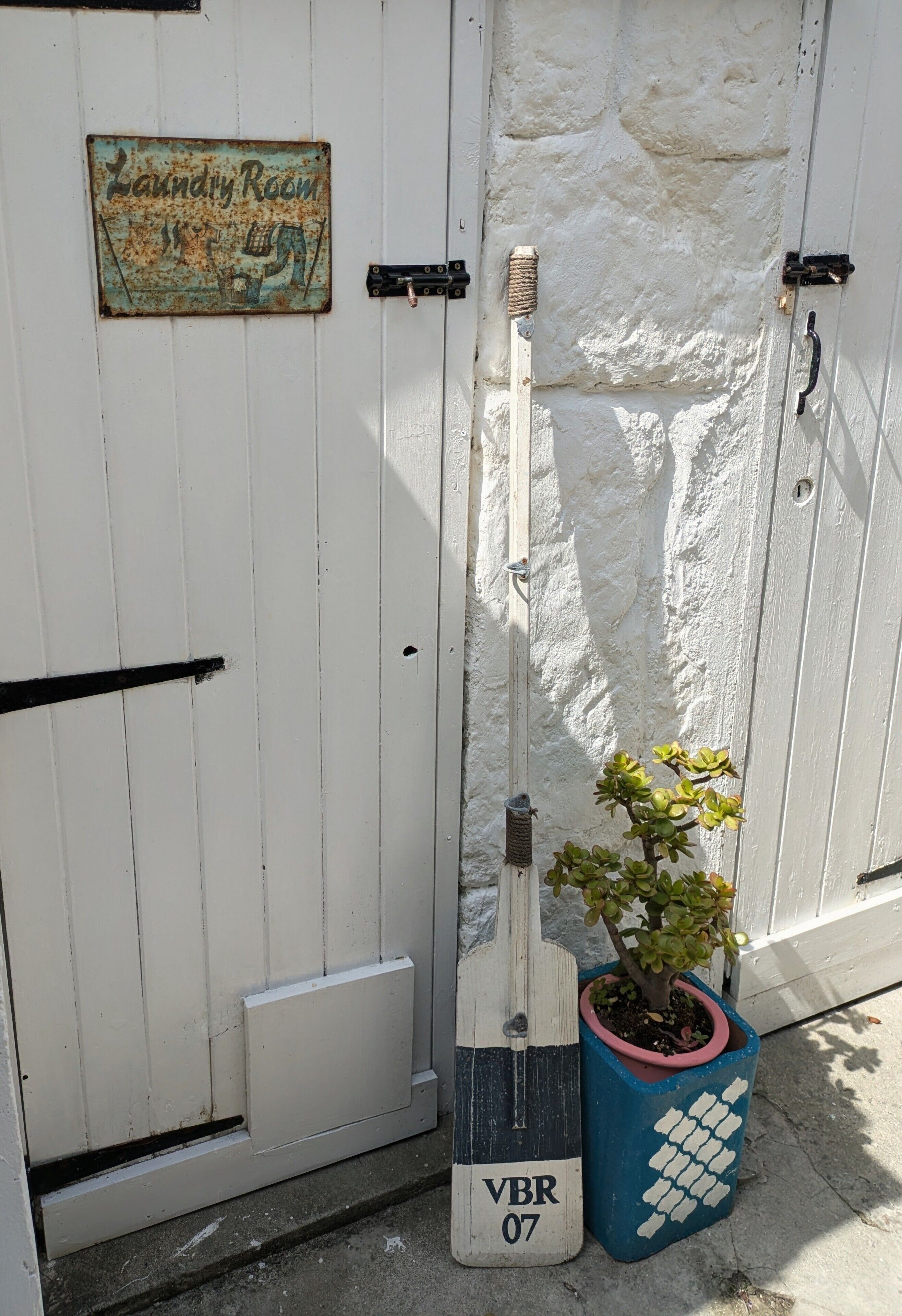 Una porta blanca amb un rètol que diu 'Laundry Room' i una planta en test amb ella.