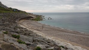 A coastal landscape with a rocky beach, a curved pathway, and a distant view of the sea. - Newly Renovated  Fisherman’s Cottage with Large Courtyard • Near Chesil Beach (PORTLAND)