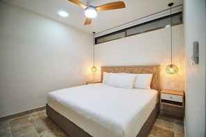 Ein Schlafzimmer mit einem Bett, einem Deckenventilator und zwei Nachttischlampen.
