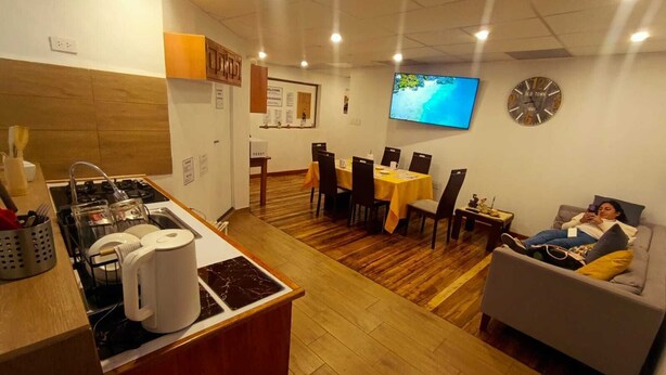 Una cocina moderna con estufa, lavamanos y zona de comedor con sillas y mesa.