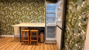 Une cuisine dotée d’un plan de travail en bois, d’un réfrigérateur et d’un mur orné d’un motif végétal.