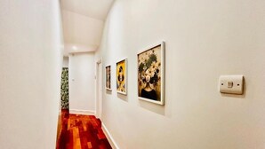 Un couloir doté d’un plancher en bois, de murs blancs et d’œuvres d’art encadrées.