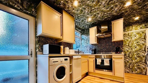 Une cuisine avec un plancher en bois, un lave-linge, un four à micro-ondes et des placards.
